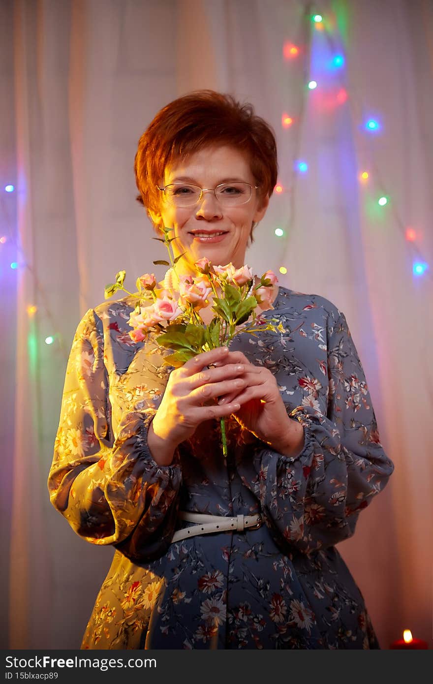 An elderly woman in a room decorated for Christmas or New Year. A middle-aged female model poses on a winter holiday