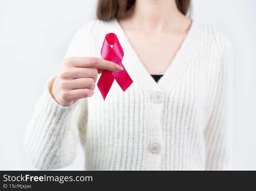 Pink ribbon in the hands of a girl. Medical diseases. Fighting cancer