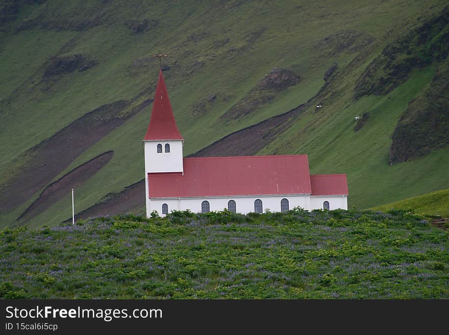 Small white church with red roof tiles in Vik, Iceland - during summer
