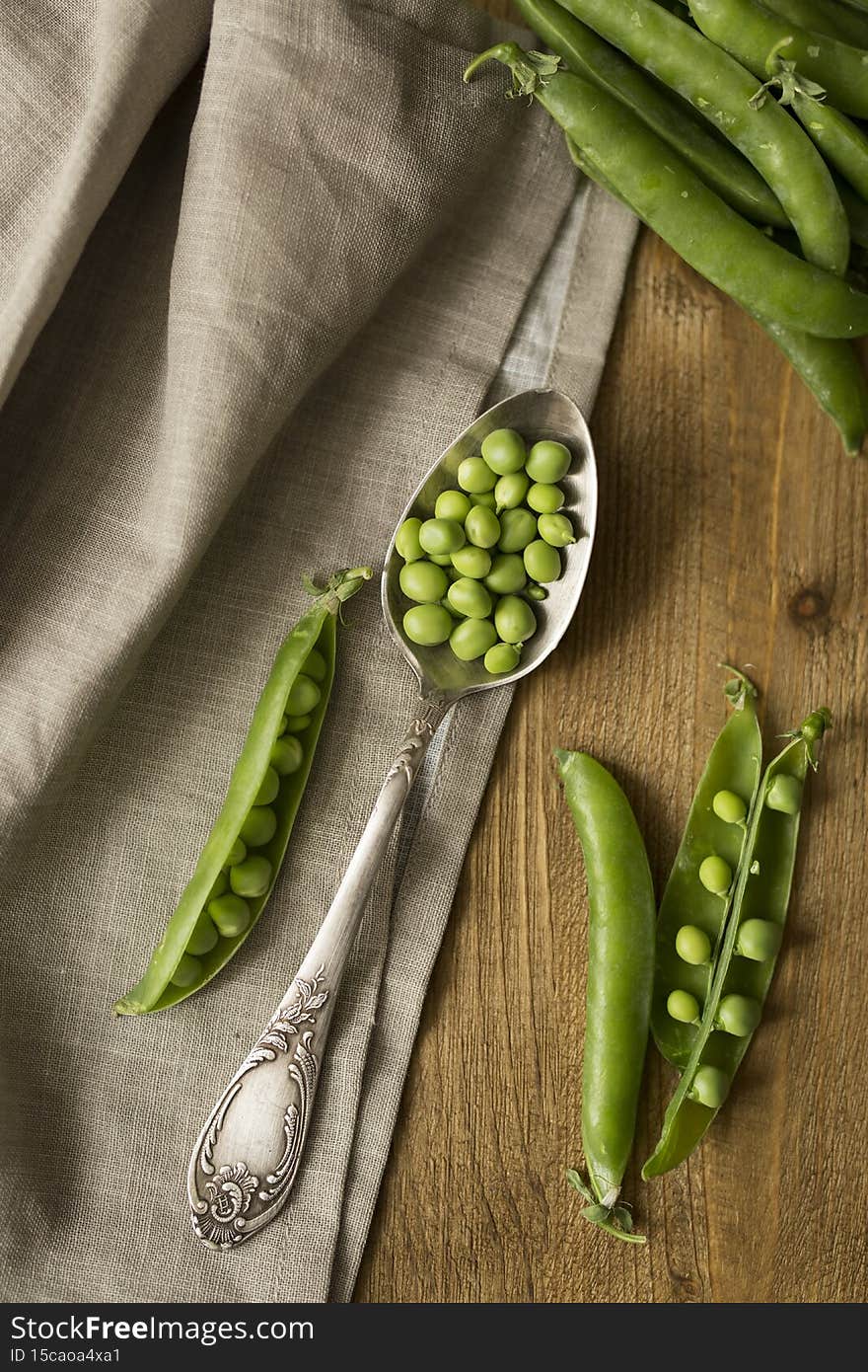 The concept of proper nutrition. Spoon with fresh green peas on wooden table. The concept of proper nutrition. Spoon with fresh green peas on wooden table