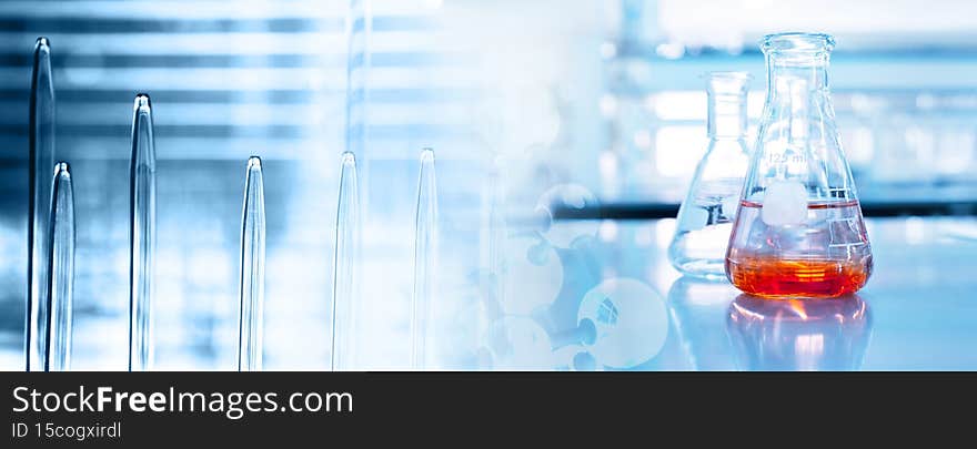 Orange solution in science glass flask in blue chemistry research school lab banner background