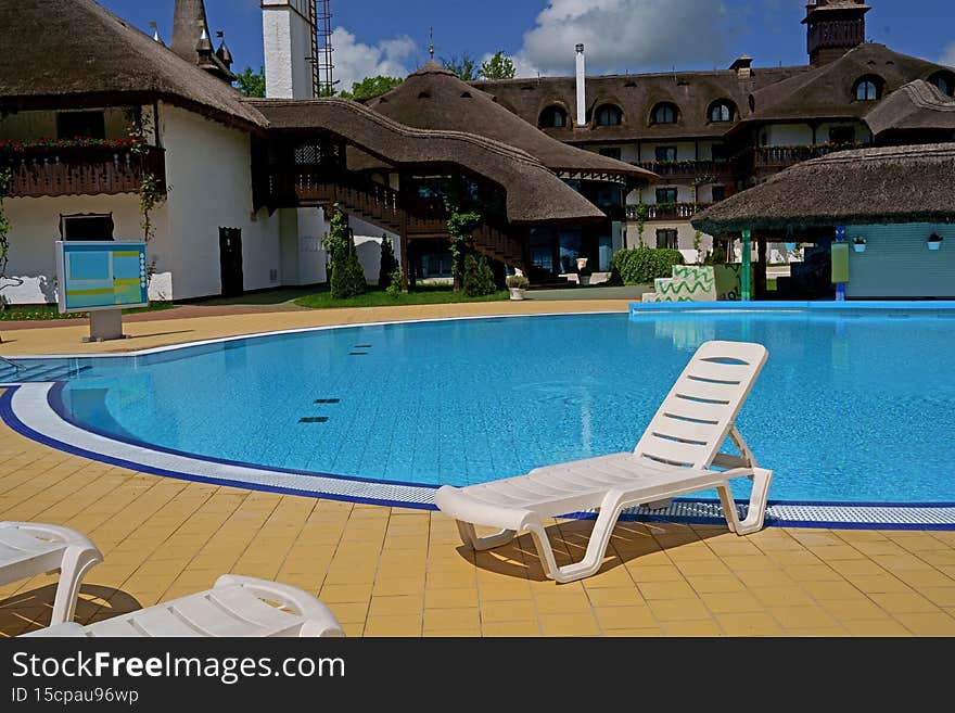 White loungers near the swimming pool on a summer day.