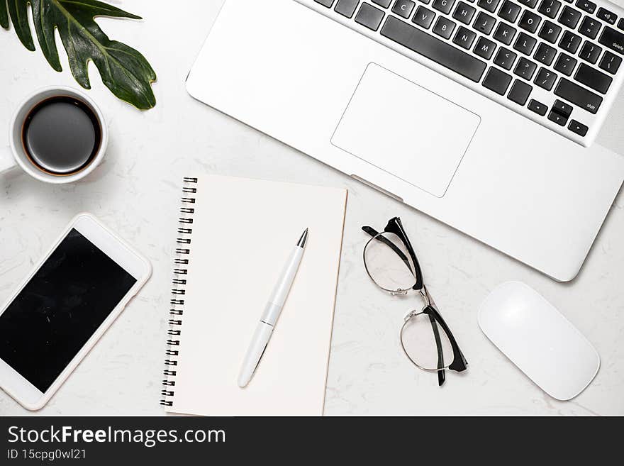 Top view photo of workplace white keyboard mouse open spiral notebook cup of coffee binder clips and pen on white table. Workspace in office