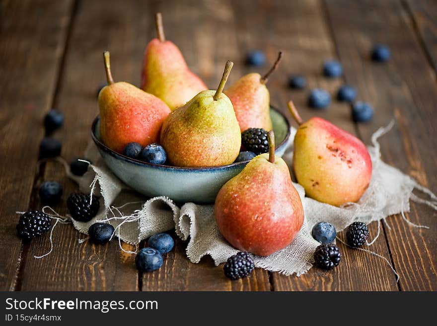 On the plate and on the table pears, blackberries, blueberries.