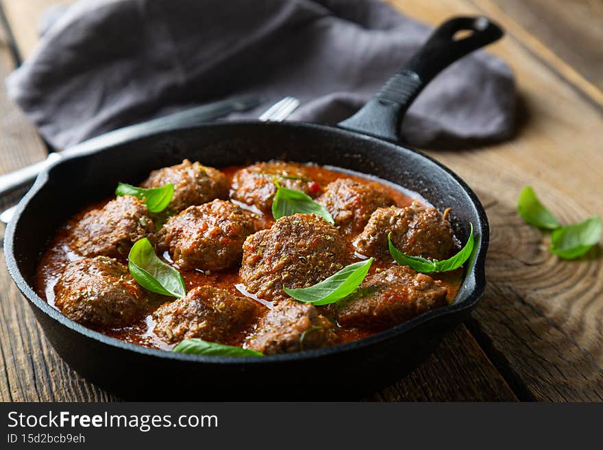 Homemade meatballs in tomato sauce with fresh basil on the table
