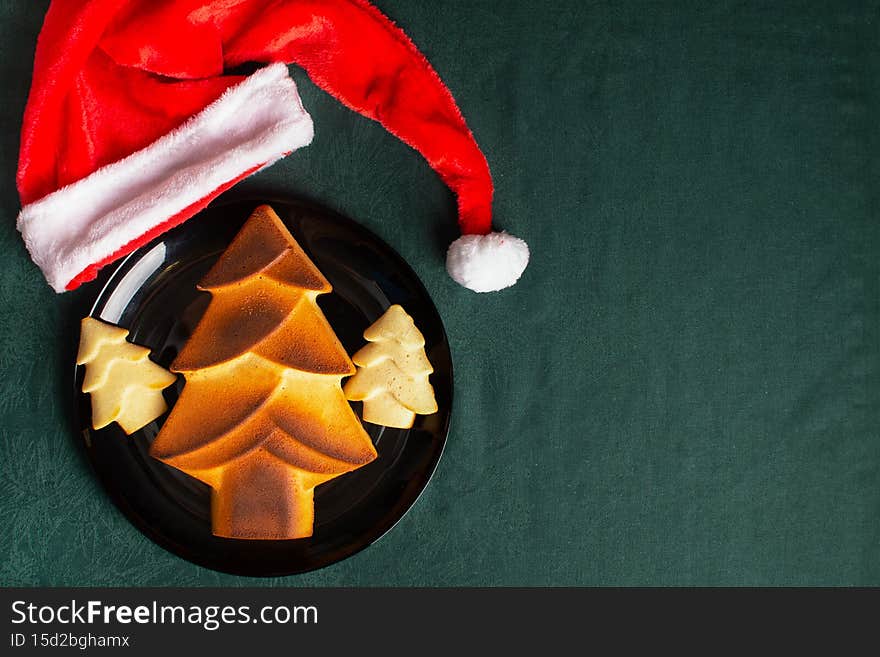 Christmas edible do-it-yourself baked Christmas trees made of pastry dough. Good New Year spirit. Giant cookies on a green background, close up with Santa Claus hat. Christmas edible do-it-yourself baked Christmas trees made of pastry dough. Good New Year spirit. Giant cookies on a green background, close up with Santa Claus hat