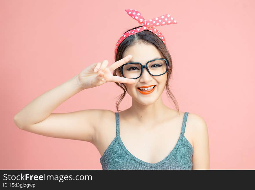 Attractive  lady making v-sign near eyes isolated on pink background.