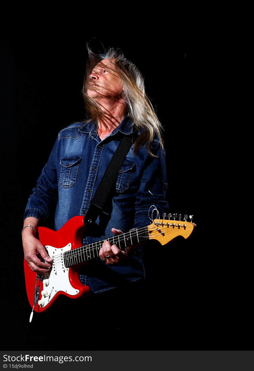 Elderly man with long gray hair plays the electric guitar