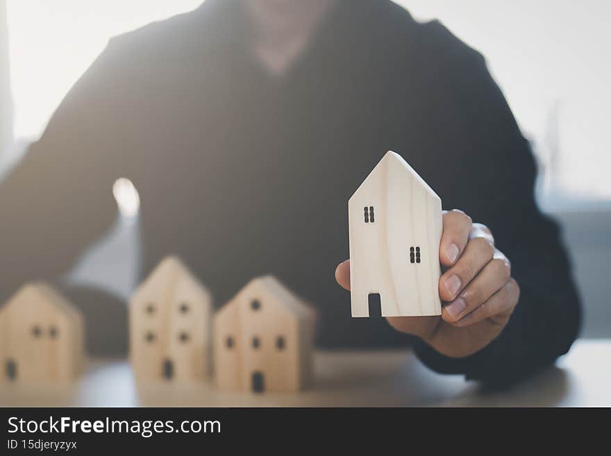 Man hand choosing mini wood house model from model on wood table, Planning buy Real Estate, Planning to buy property. concept of C