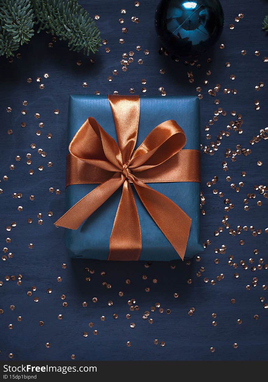 Christmas or New Year concept composition with a gift box and winter holidays decoration on the dark blue background.