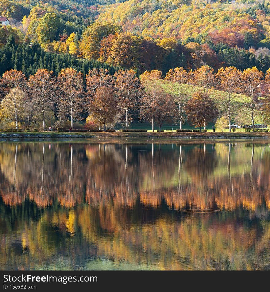 Stubenbergsee mirror lake surrounded by dense forest in the fall colors