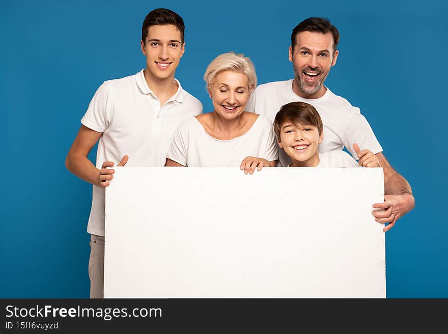 A wonderful happy family wearing white tshirts- two sons, mom and dad. Smiling, friendly people pose in the studio, holding a