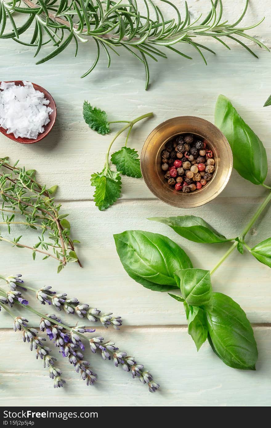 Aromatic herbs with salt and pepper, top shot on a rustic wooden background. Rosemary, lemon balm, basil, thyme, and lavender