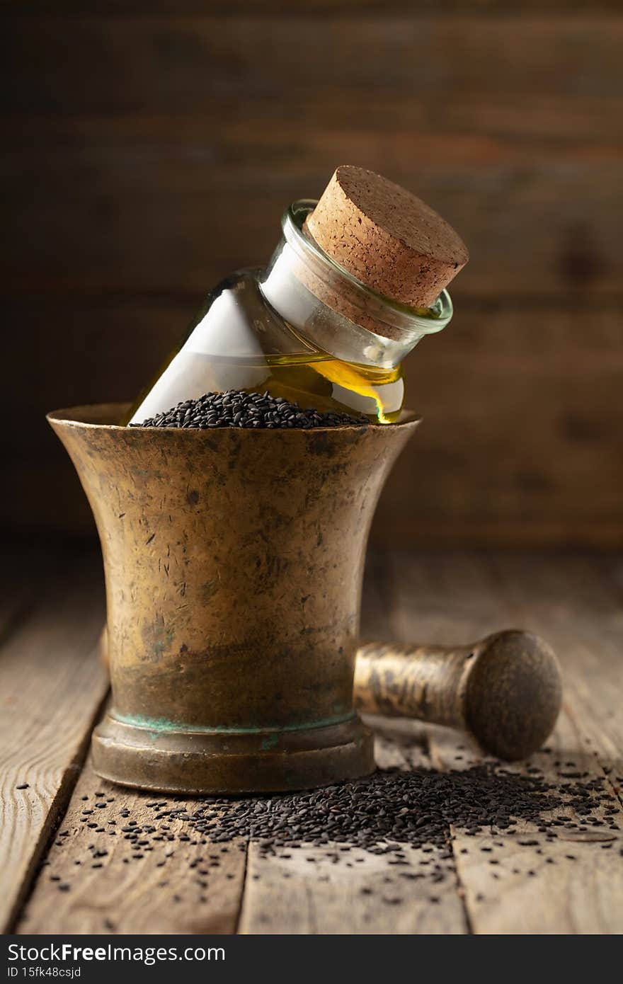 Black sesame and a small bottle with oil in an old brass mortar