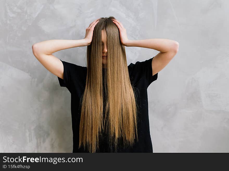 Beautiful lady doing her make up and hair in bedroom. Attractive young female with pretty long hair