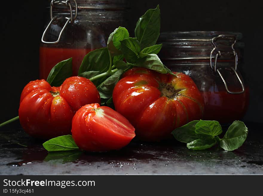 Still life with tomatoes, tomato juice and basil on a black background. Still life with tomatoes, tomato juice and basil on a black background