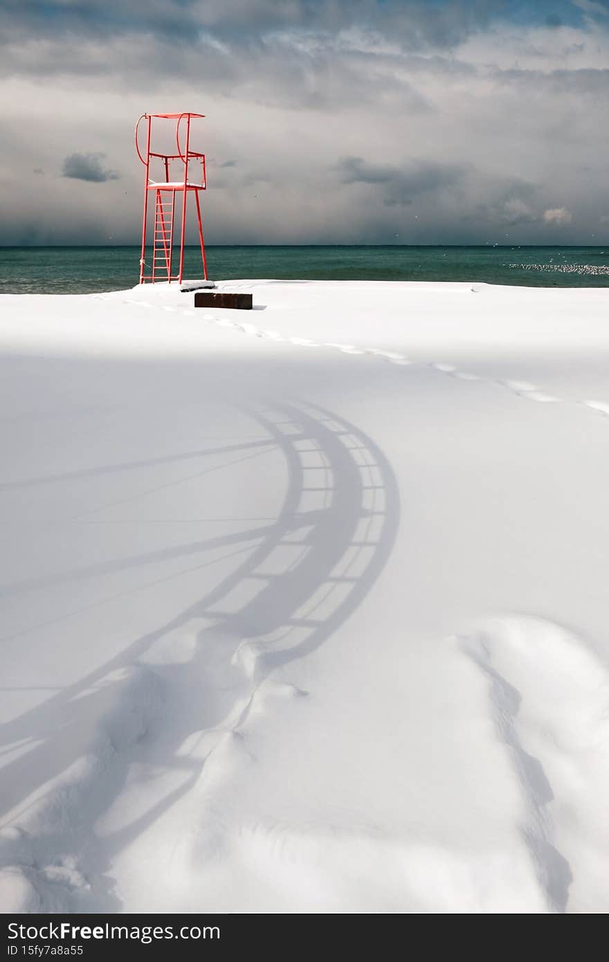 Red lifeguard tower construction on the beach covered with snow
