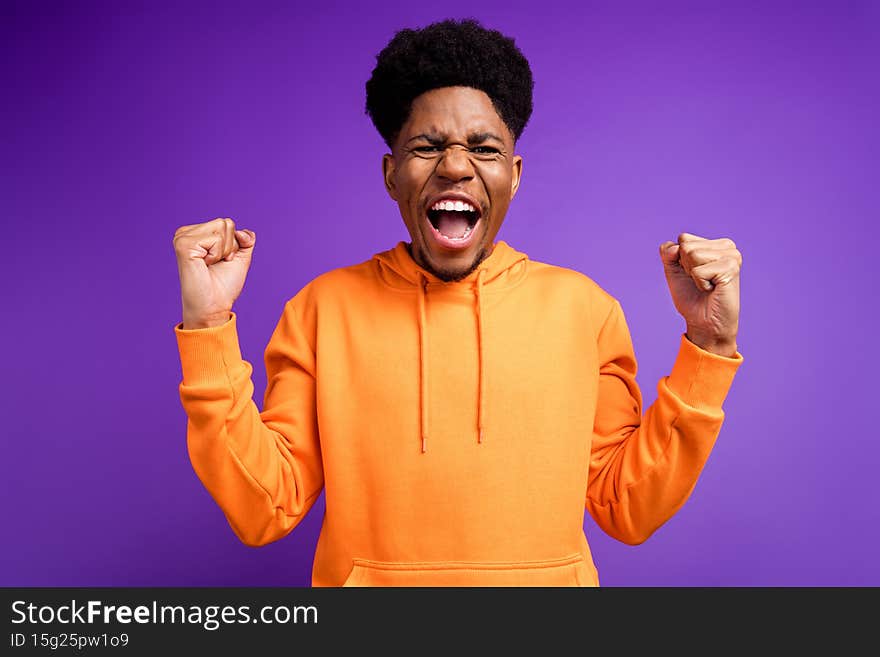 Photo of cheerful young dark skin man winner good mood celebrate champion fists isolated on purple color background