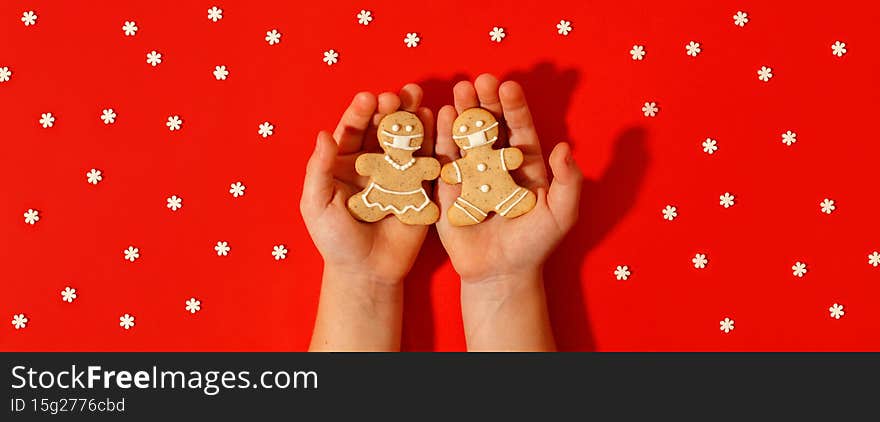 Happy 2022 New Year`s set of cookies, gingerbread man, woman in face  from ginger biscuits glazed sugar decoration in kids hands on red background, minimal seasonal pandemic winter holiday