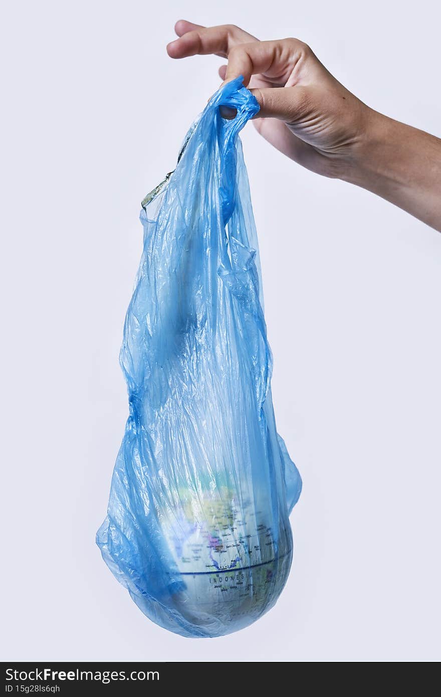 Global Warming and Climate Change concepts. Woman hand holds a glove in plastic bag. Environmental conservation. World globe in a plastic bag. Environmental pollution. The planet is in danger