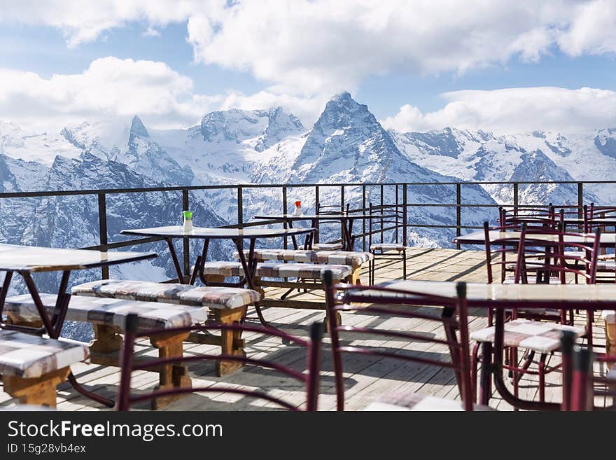 An open-air cafe high in the snow-capped mountains on a clear, sunny day. Winter sports and outdoor activities