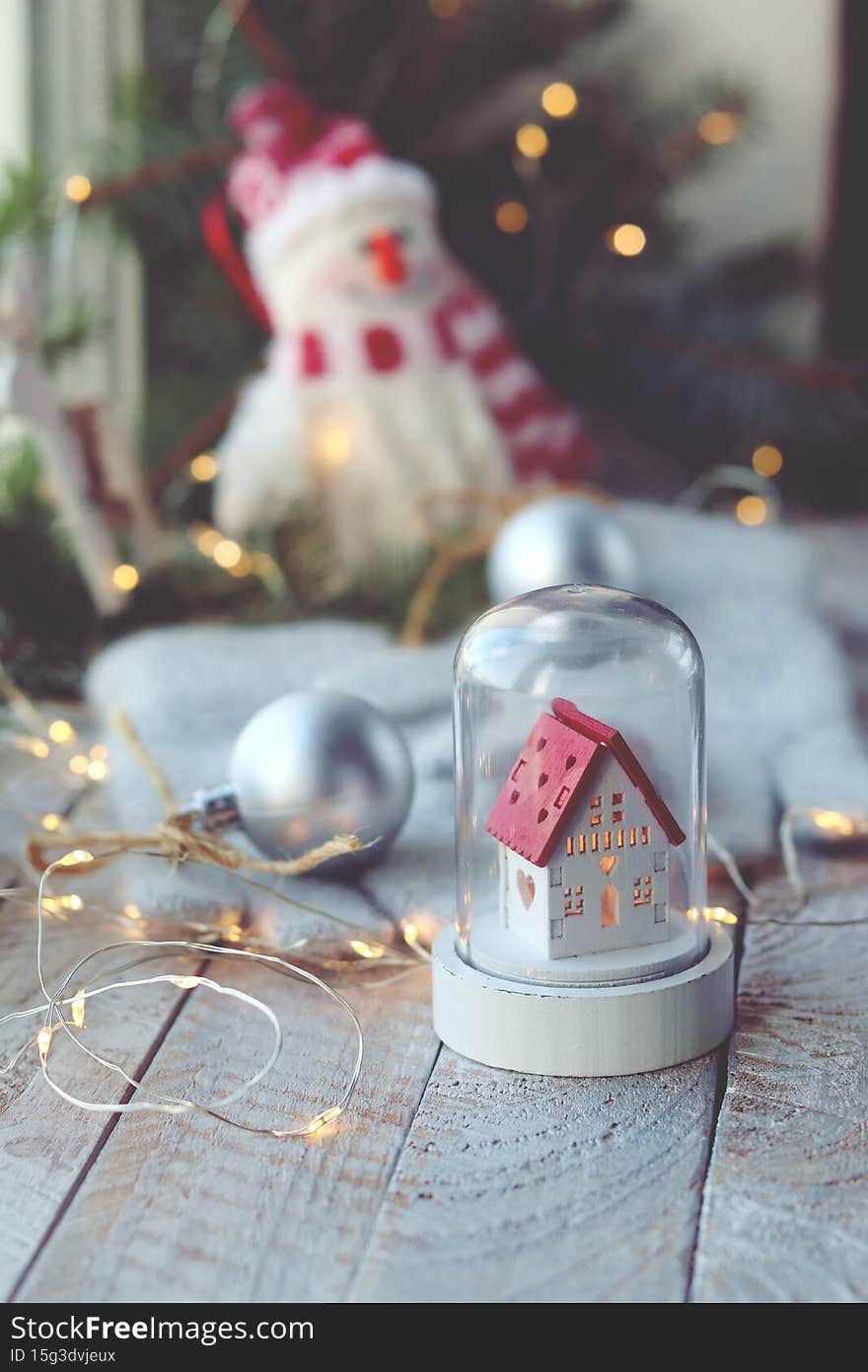Christmas toys, a snowman and a house, balls, spruce branches, illumination on a wooden windowsill