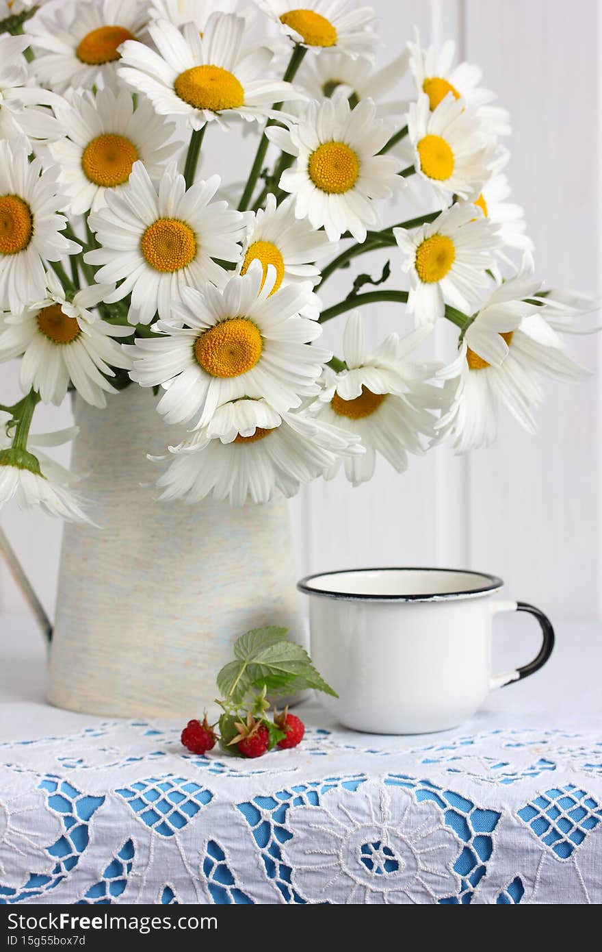 Bouquet of daisies in a jug enameled mug and raspberries