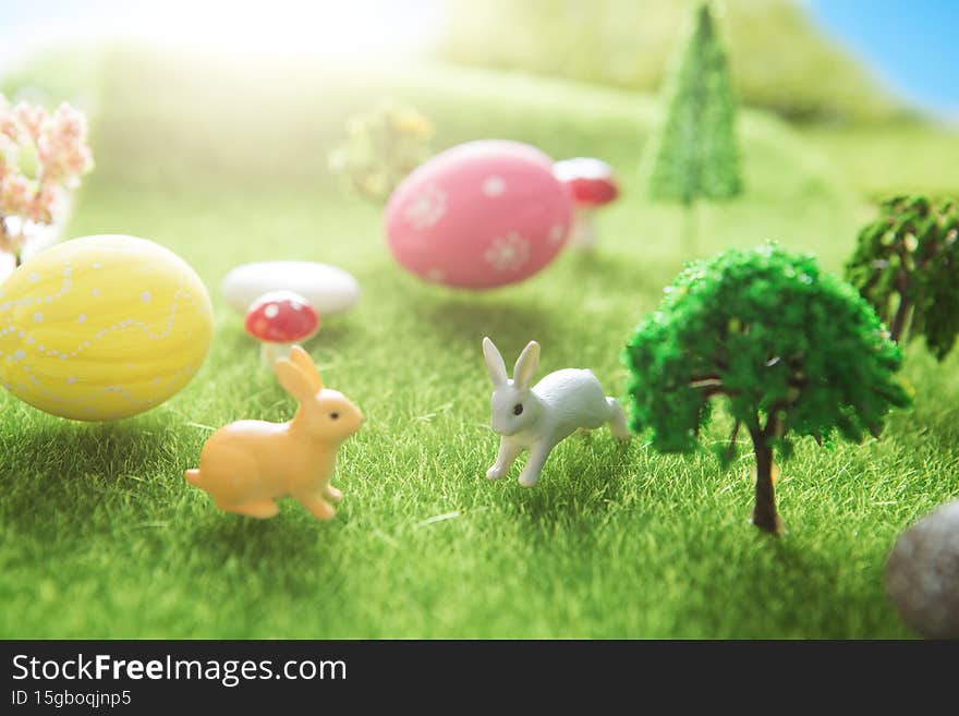 Rabbit toys with easter eggs on a meadow grass. Yellow easter egg spring meadow with two rabbit and easter eggs. Fairy