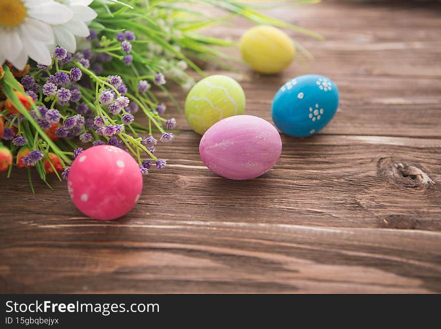 Colorful Easter eggs and spring flowers on rustic wooden background.