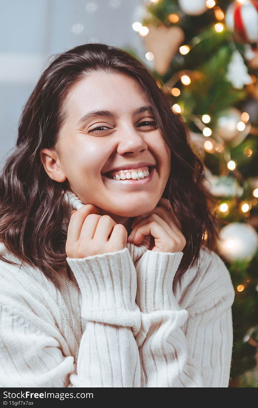 woman in white sweater posing near christmas tree