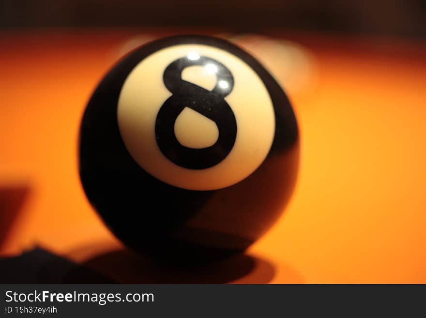 Pool ball number 8 in soft focus close-up on a blurred background.