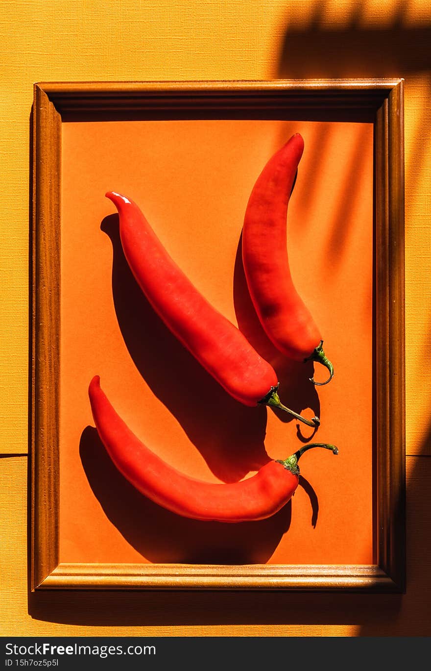 Flat lay Red fresh hot chili pepper in a frame on red and pink background