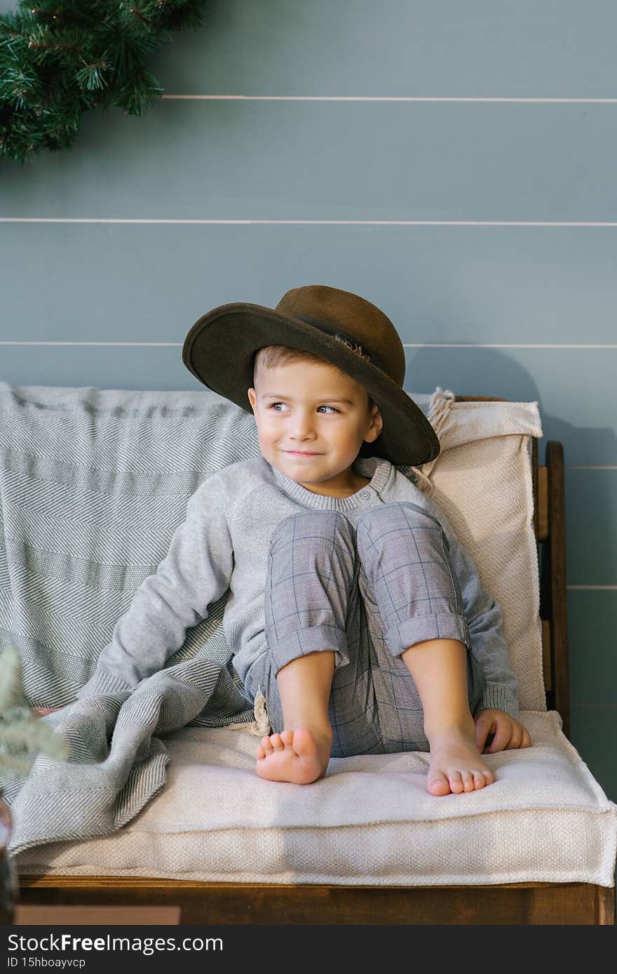 Prankster a happy child boy is sitting on the sofa in a hat that he took from his mother