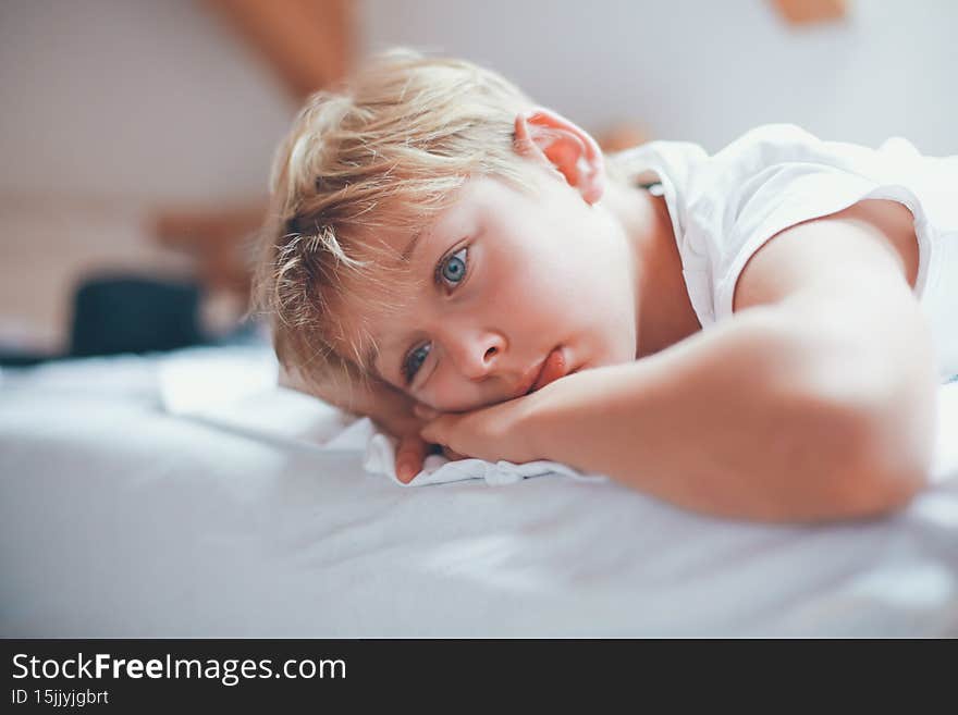 A boy is lying on a bed and looking really bored. A boy is lying on a bed and looking really bored