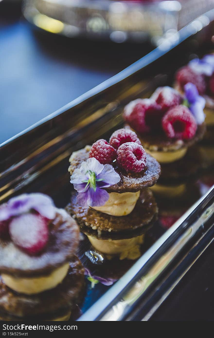 A vertical shot of delicious tarts with raspberries and chocolate on a table