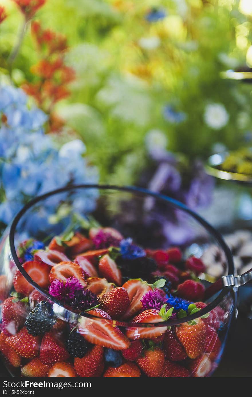 Vertical shot of a fruit salad with strawberries and blackberries in a glass bowl