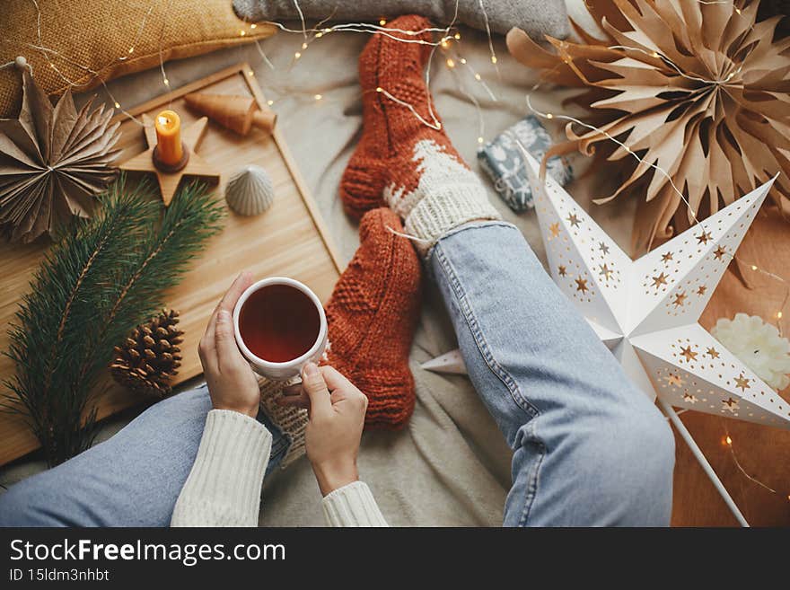 Woman hands with warm cup of tea and festive holiday decorations Top view. Christmas winter hygge