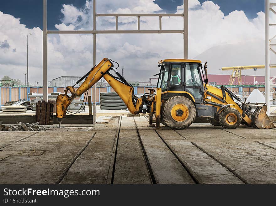 Professional demolition of reinforced concrete structures with an industrial hydraulic hammer with an excavator. Dismantling the concrete floor in the production area. Debris and crumbs of concrete.