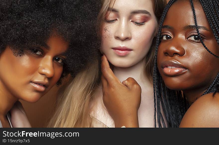 young pretty african and caucasian women posing cheerful together on brown background, lifestyle diverse nationality people concept close up