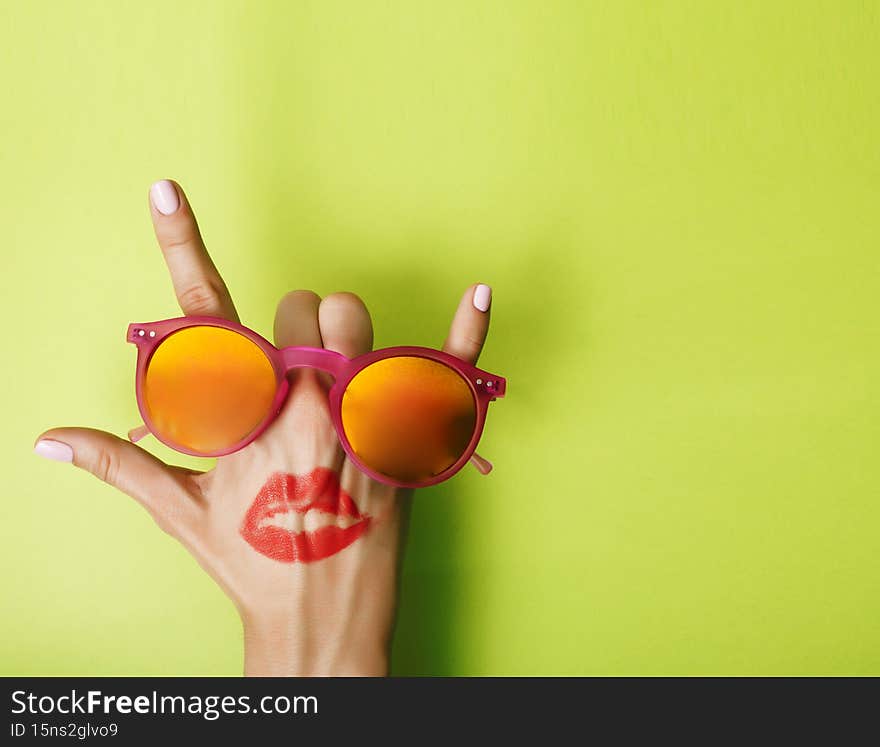 woman hand holding sunglasses on bright background, cosmetic summer vacation concept