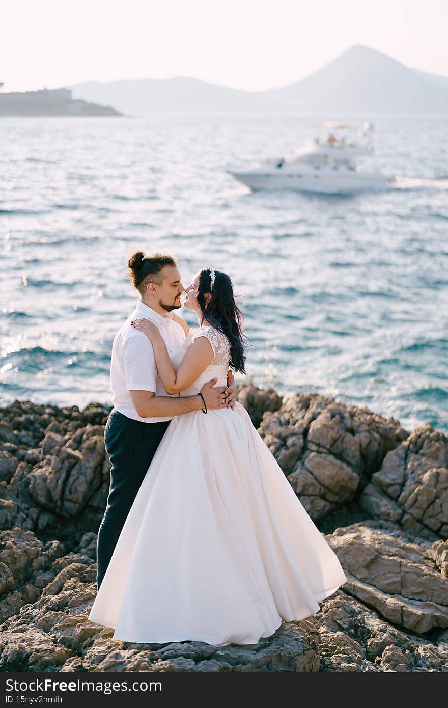 Bride and groom hug on the stones and almost kiss