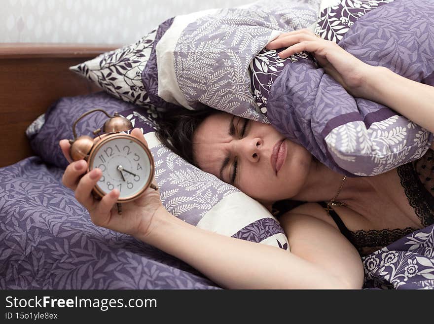 Sleepy woman covered with a blanket looks angrily