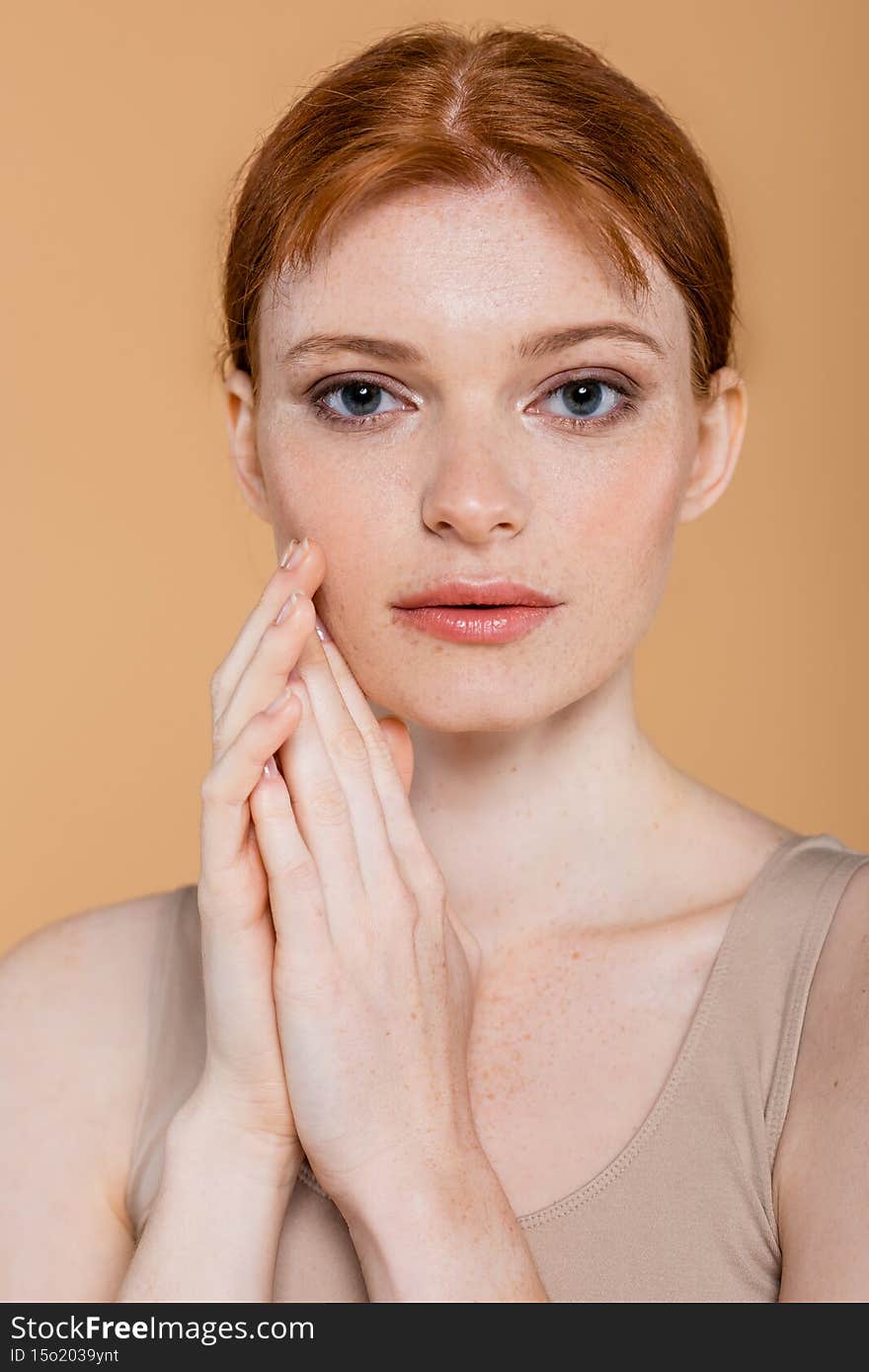 Young redhead woman with perfect skin looking at camera  on beige,stock image