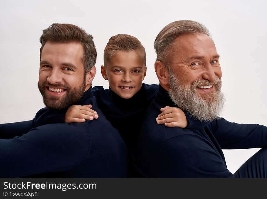 Portrait of happy small oy child kid hug young father and old grandfather show gratitude. Smiling three generations of men demonstrate family unity bond. Children and parent support. Fatherhood. Portrait of happy small oy child kid hug young father and old grandfather show gratitude. Smiling three generations of men demonstrate family unity bond. Children and parent support. Fatherhood.