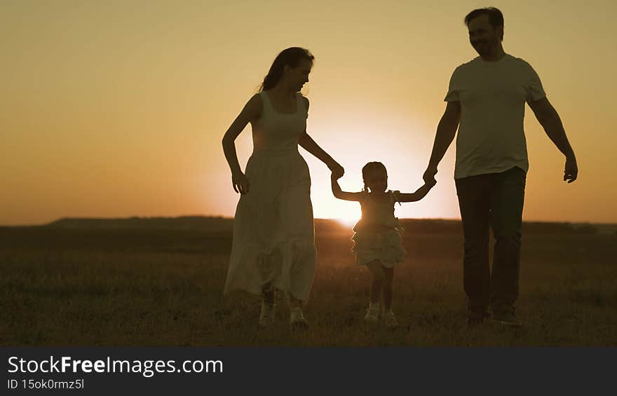 Happy father and mother run across field with small child sunset in sky, silhouette cheerful family, childhood dream of