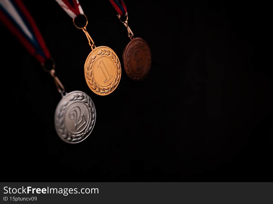 Gold, silver and bronze medals with numbers on black isolated background for winners