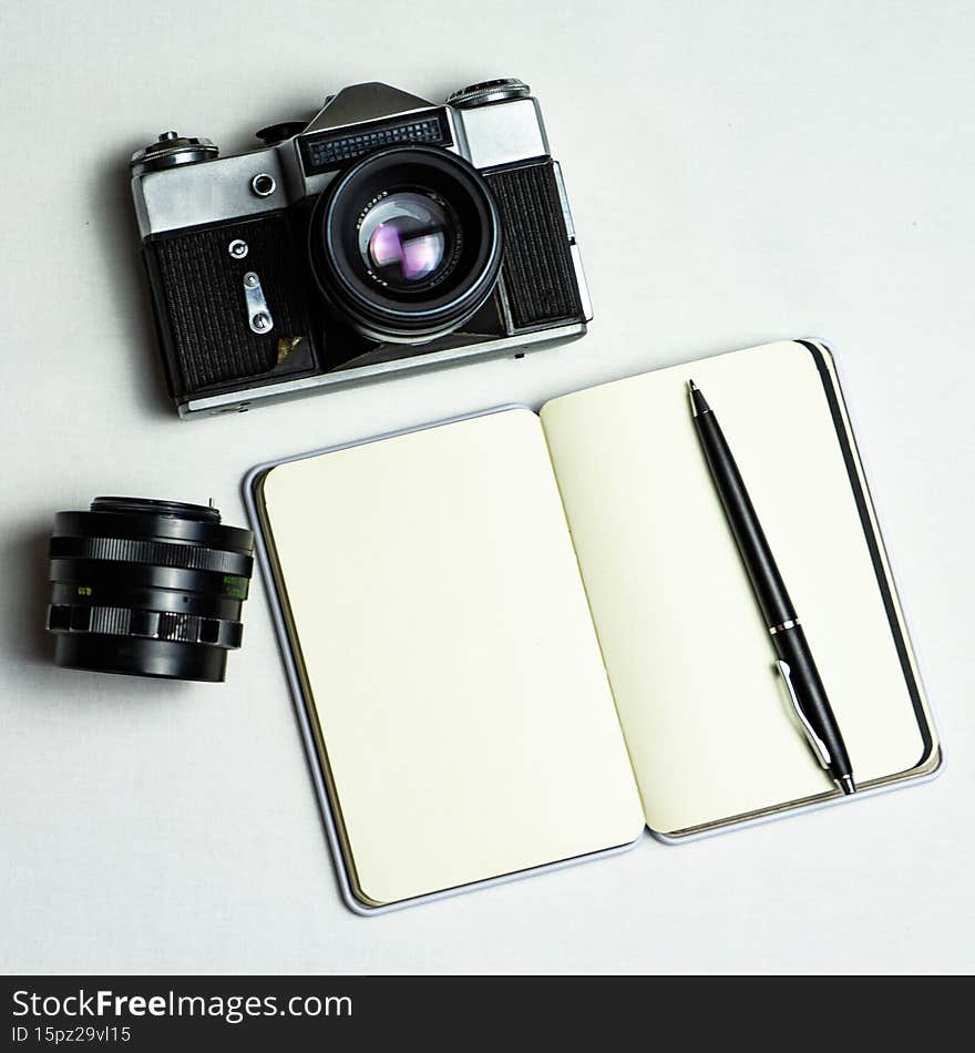 Old analogue camera and notepad. A clean notebook with a fountain pen and a retro camera on the table.