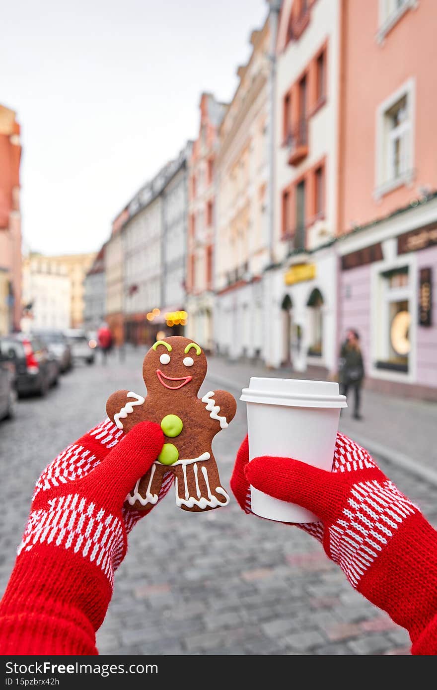 Christmas market in old town European small city. Hand holding a smiling gingerbread man and christmas mood in blurred background. Christmas market in old town European small city. Hand holding a smiling gingerbread man and christmas mood in blurred background