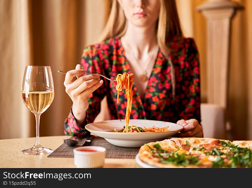 Woman eats Italian pasta with tomato, meat. Close-up spaghetti Bolognese wind it around a fork with a spoon. Parmesan
