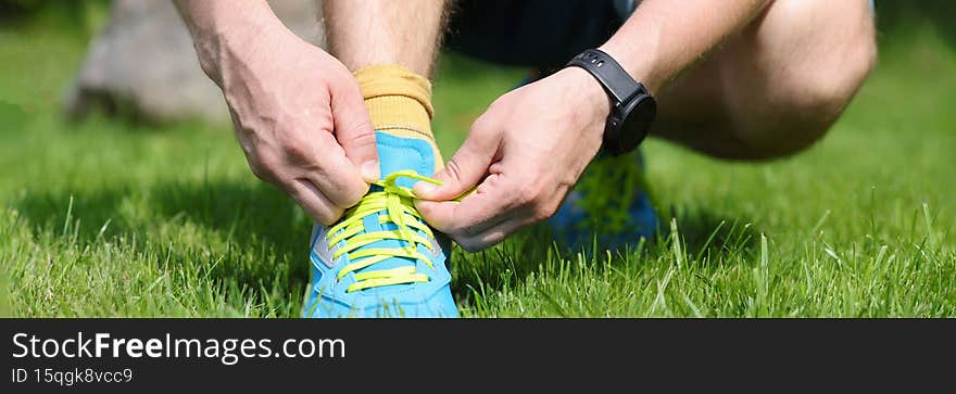 Man is tying laces on bright blue sneakers